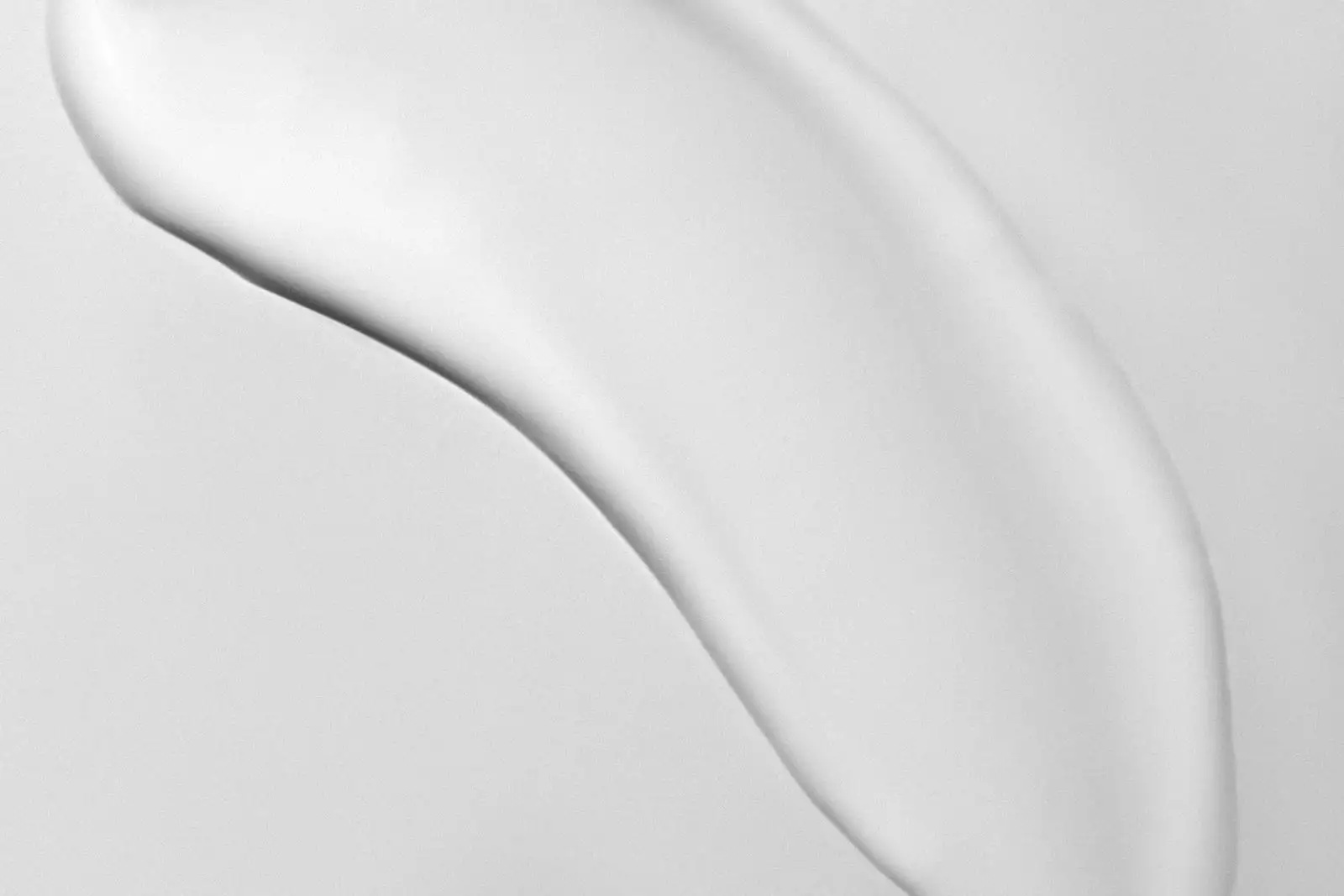 Close-up of a curved streak of white cream spread on a white surface