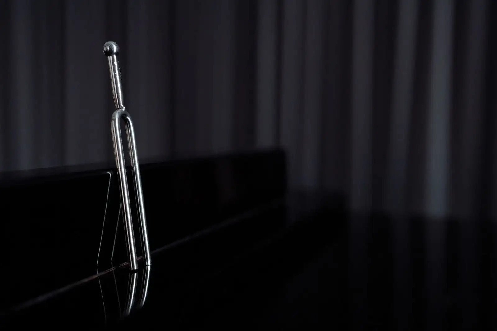 Metal tuning fork standing on a black surface, the instrument used to test hearing