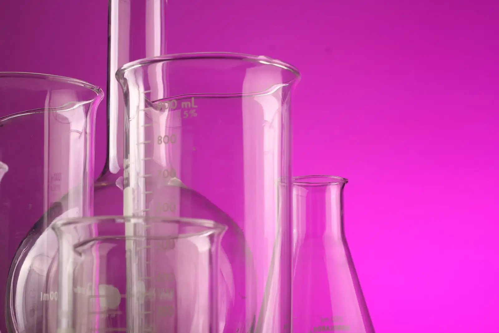 Graduated laboratory glassware, empty flasks and beakers on a magenta background