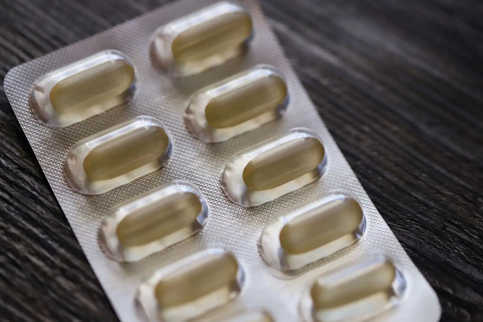 Blister pack of capsules on a wooden table, one of the medicines whose clearance CBD can change