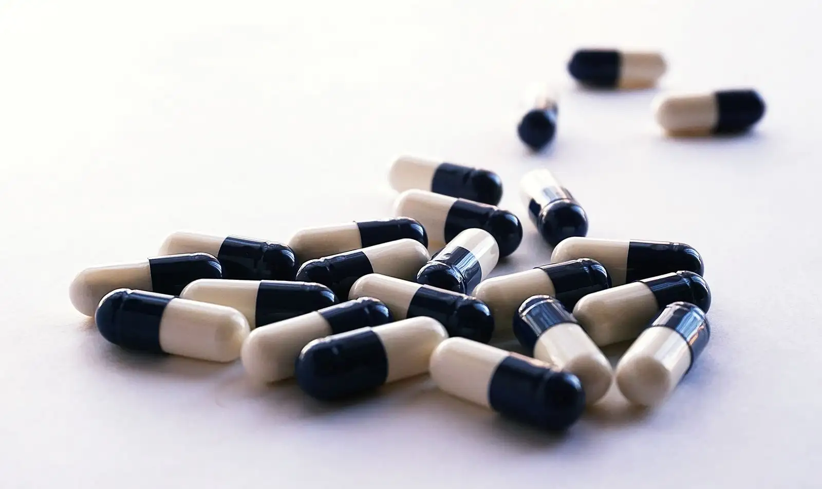 Black and white two-tone capsules scattered on a pale surface