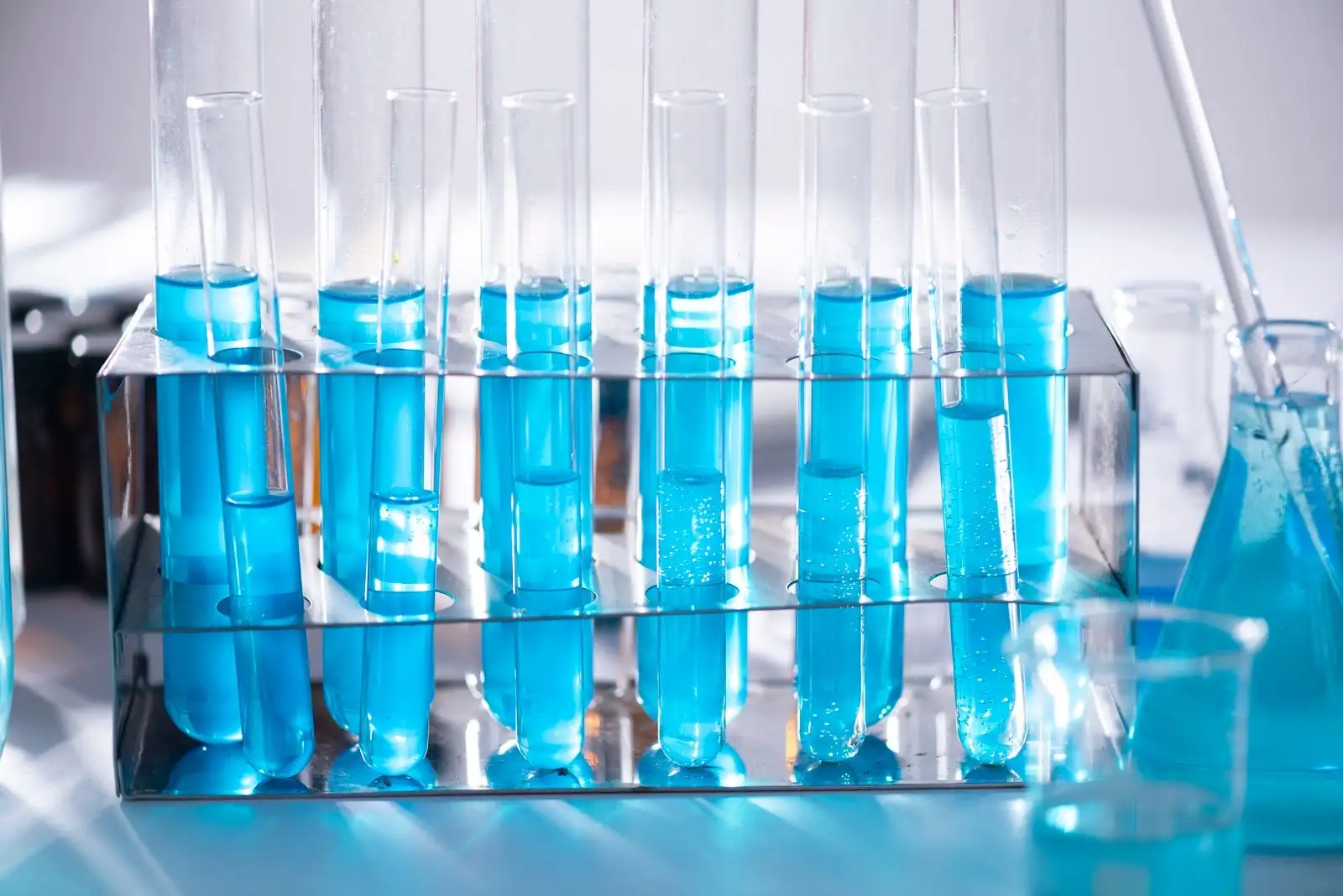 Test tubes filled with blue liquid lined up in a laboratory rack
