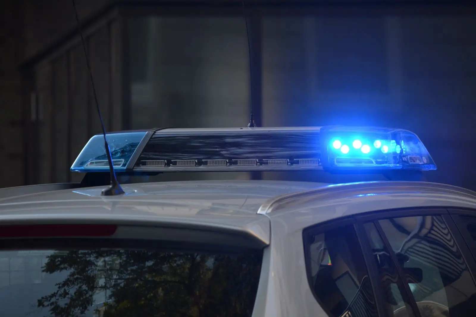 Blue light bar switched on, on the roof of a police car at night