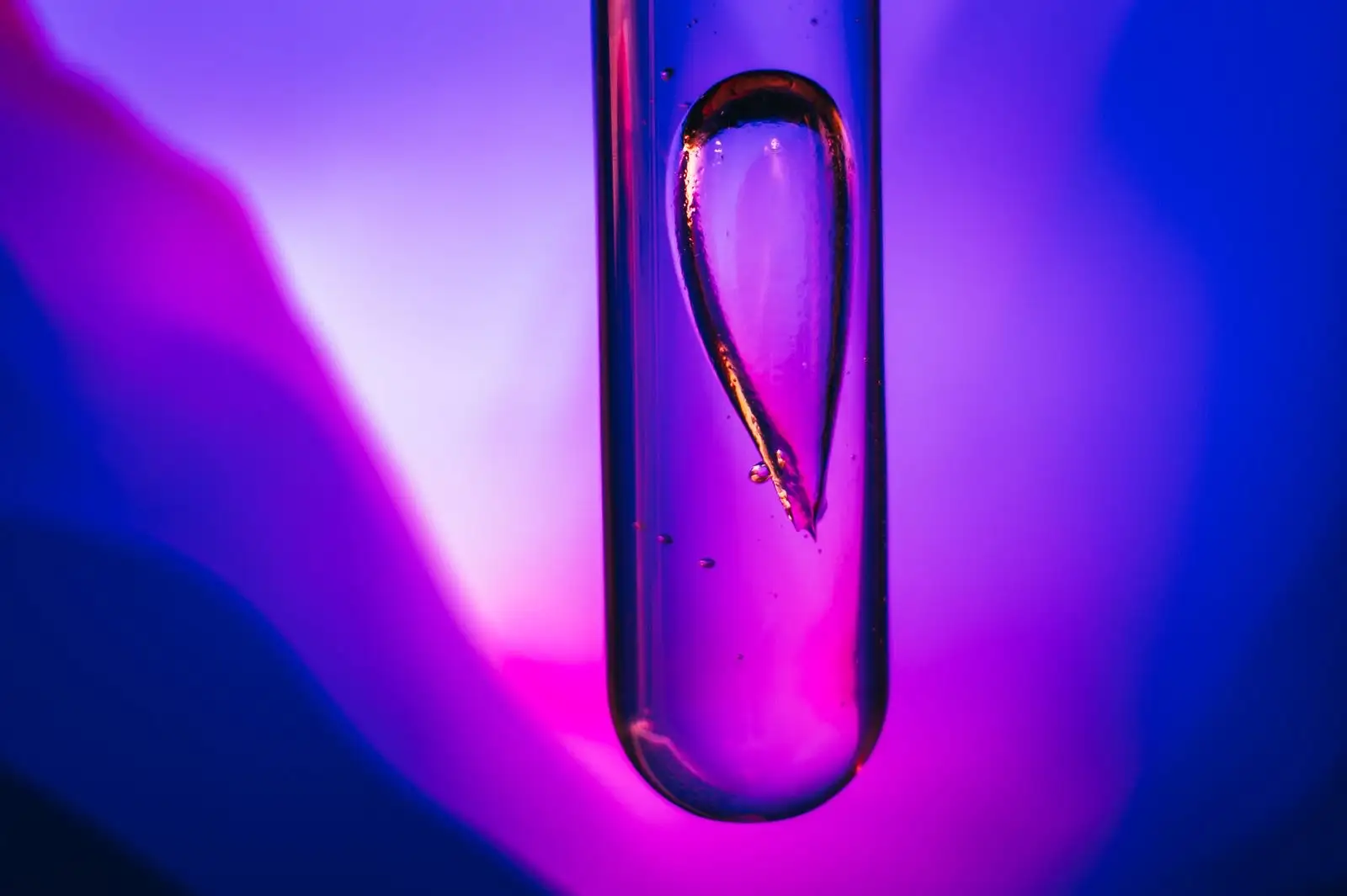 Drop of viscous liquid in a glass test tube, lit in violet