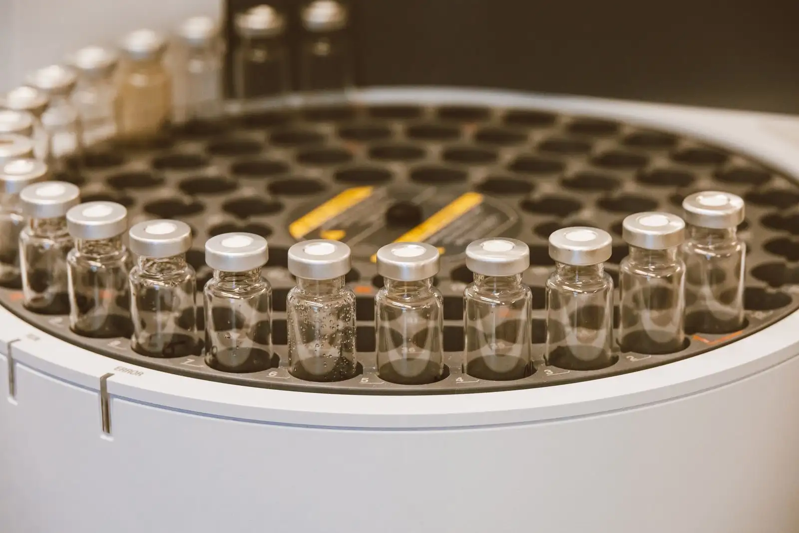 Glass sample vials lined up on the tray of a chromatograph autosampler