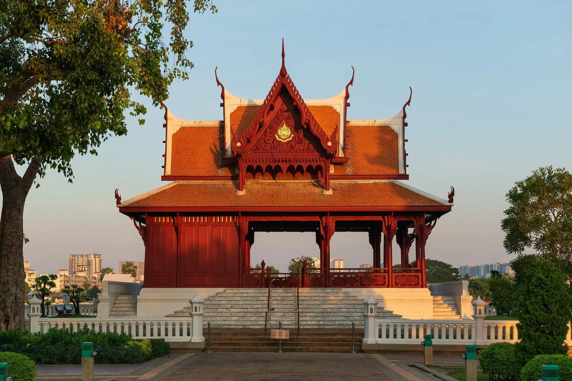 Thai-style pavilion with a red and gold roof under a clear sky.
