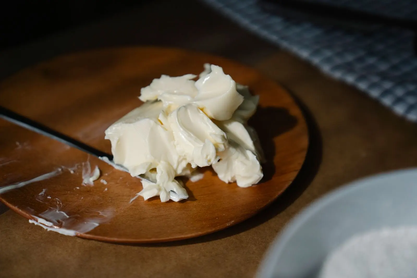 Softened butter worked with a knife on a round wooden board