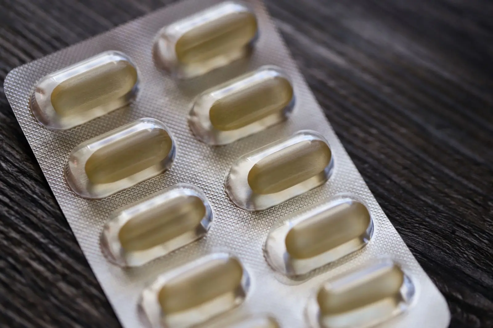 Blister pack of capsules on a wooden table, one of the medicines whose clearance CBD can change