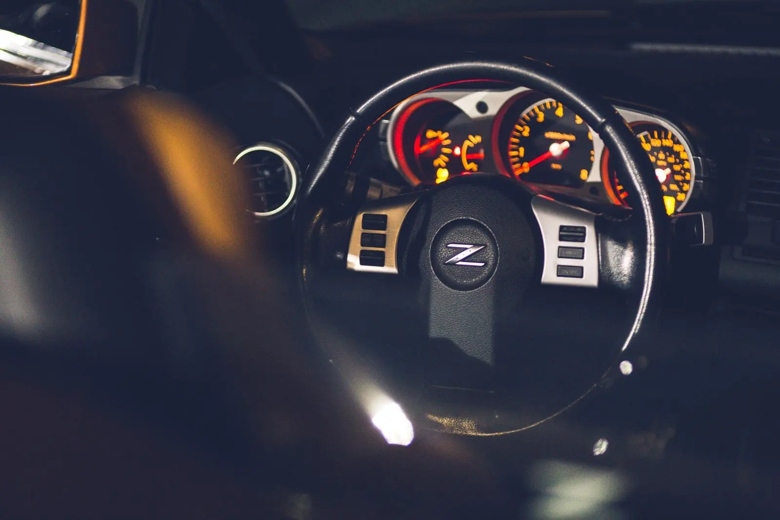 Steering wheel and lit gauges of a car at night, seen from the driver's seat
