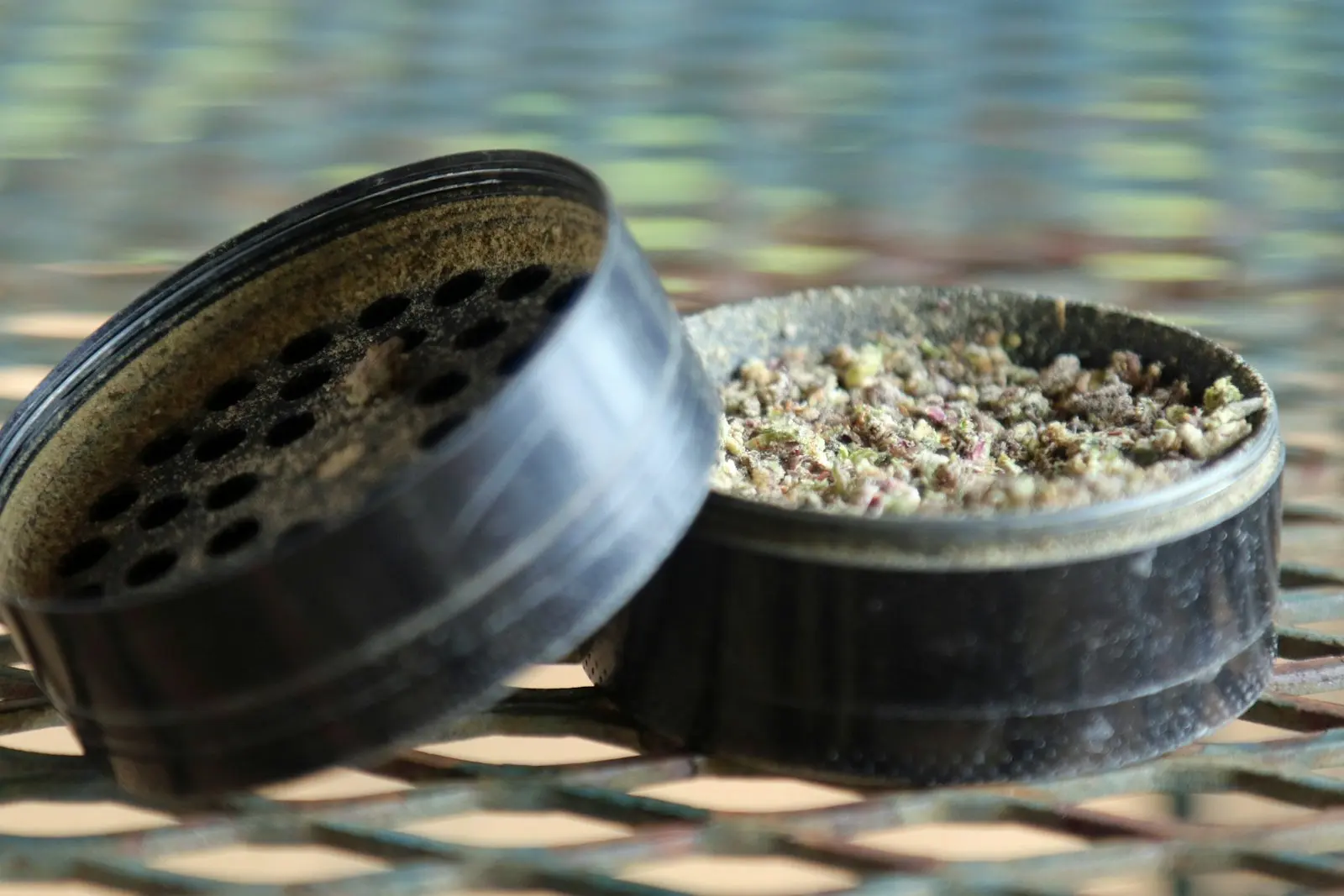 An open two-piece grinder, its chamber filled with finely ground flower