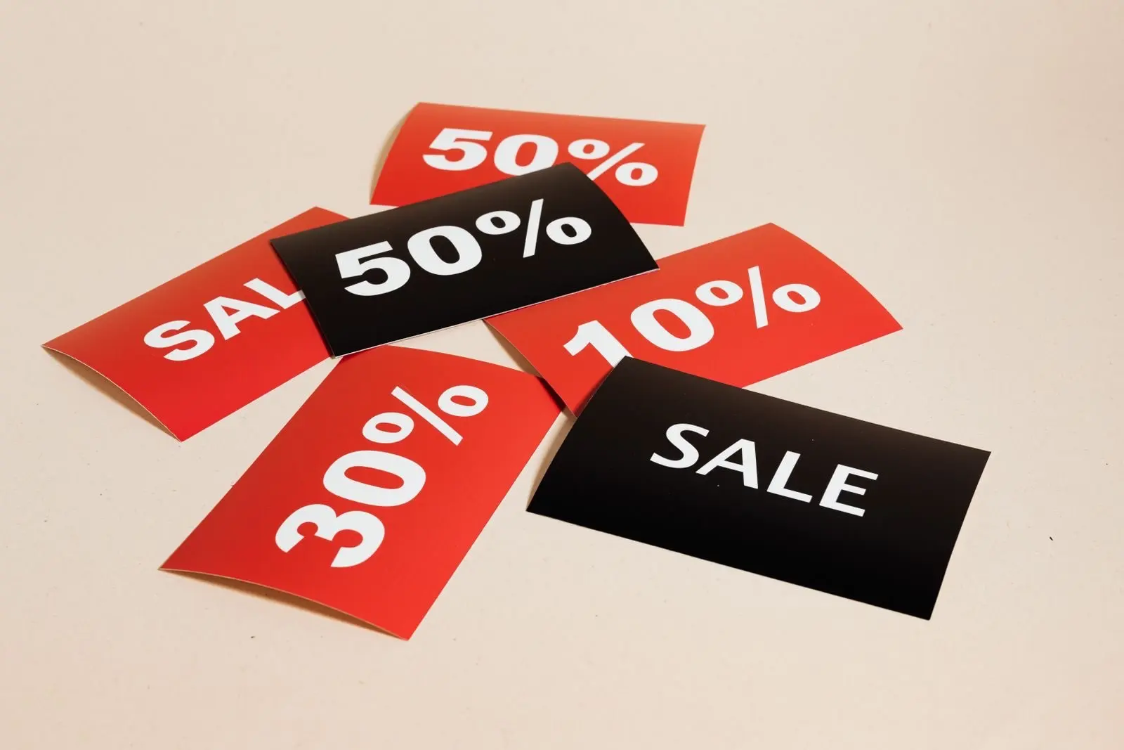 Red and black sale tags marked 10%, 30% and 50%, lying on a beige background