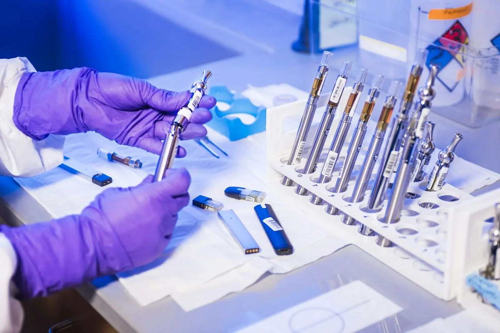 Gloved hands examining e-cigarettes in a testing laboratory, where synthetic cannabinoids are identified
