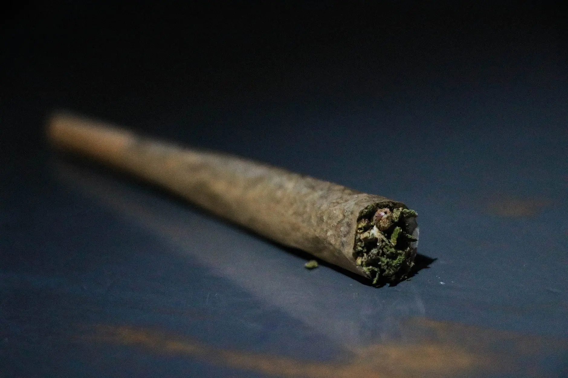 A rolled joint on a blue surface, close up; illustrative photo.