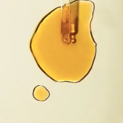 Goutte d’huile ambrée déposée par une pipette