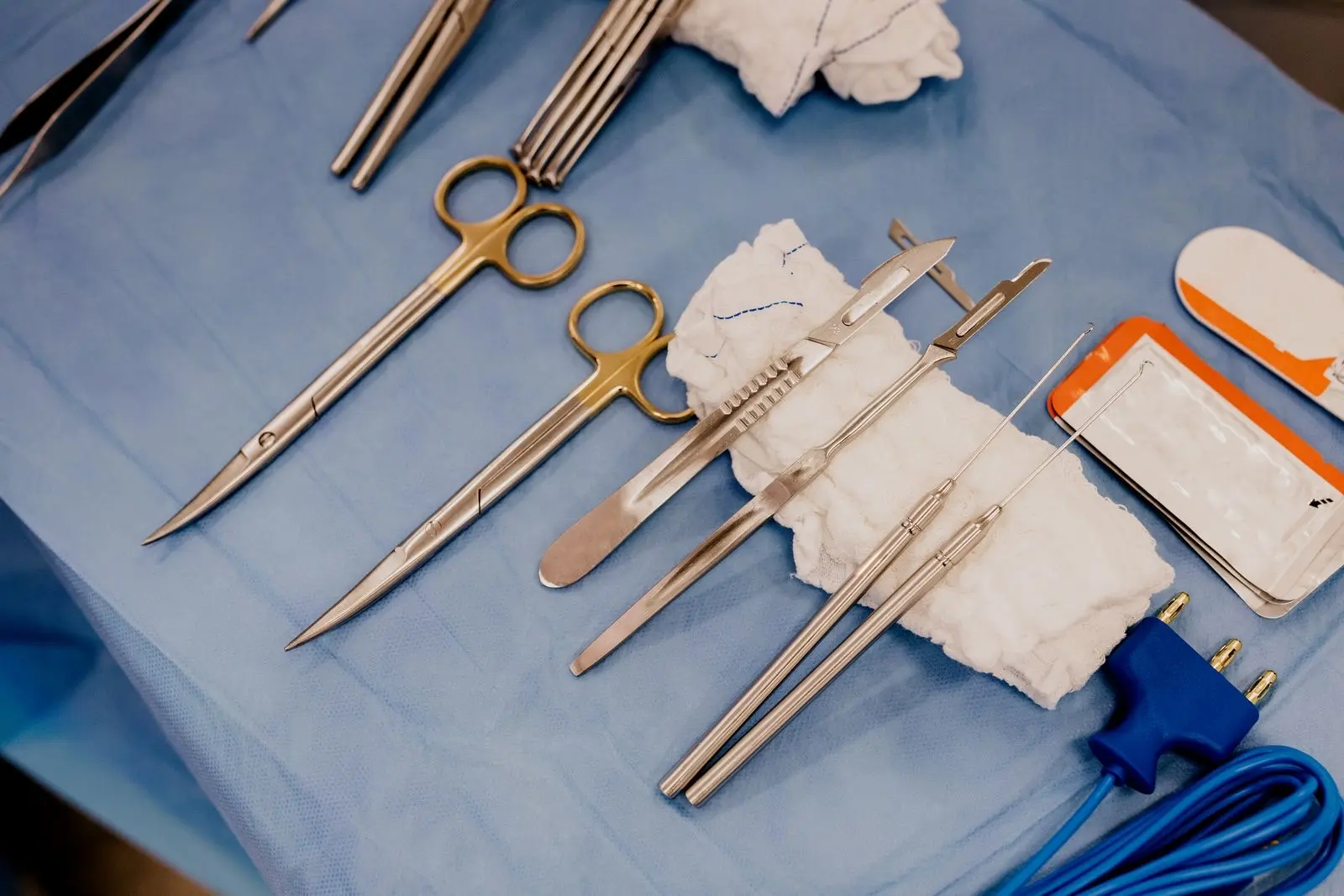 Sterile surgical instruments laid out on a blue drape in an operating theatre