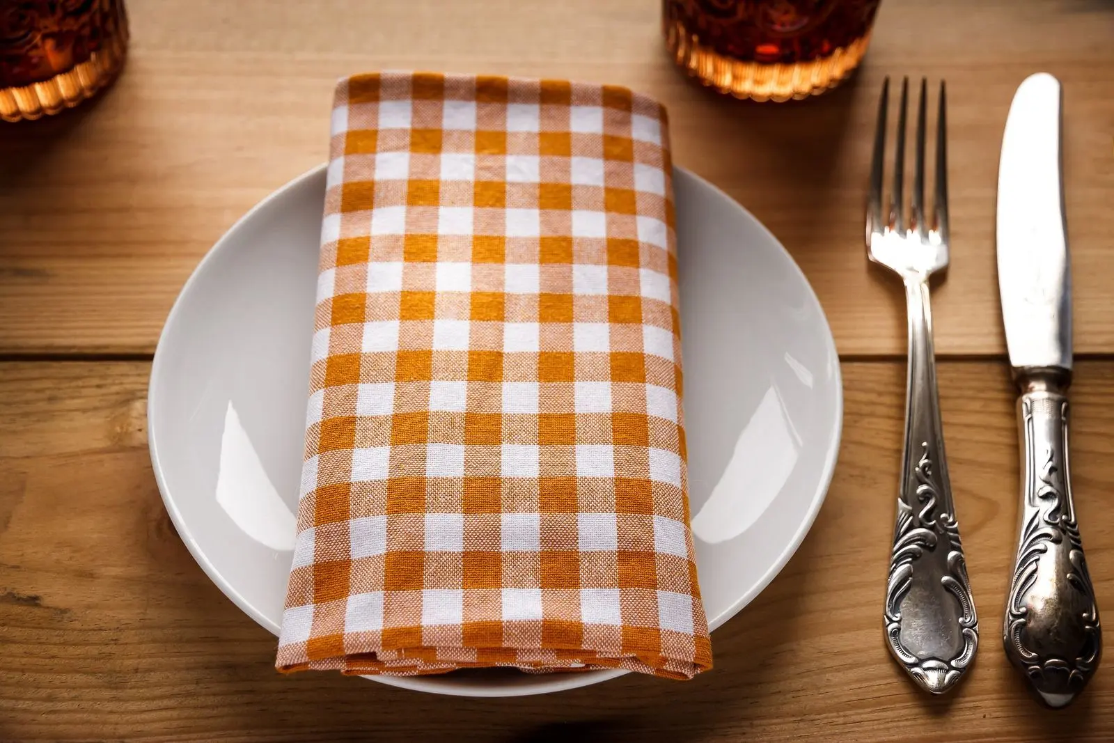 Empty plate with a checked napkin, fork and knife on a wooden table