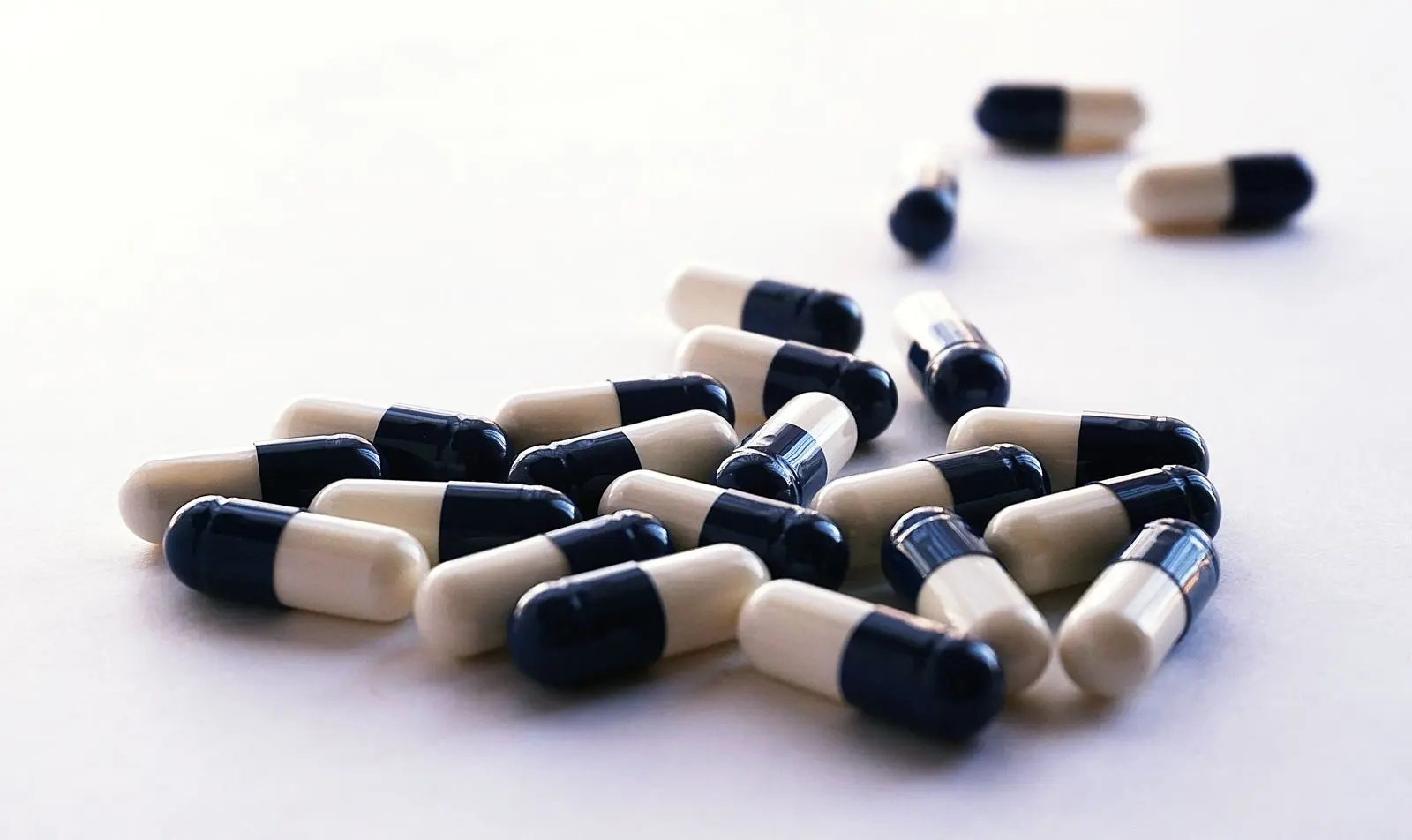 Black and white two-tone capsules scattered on a pale surface